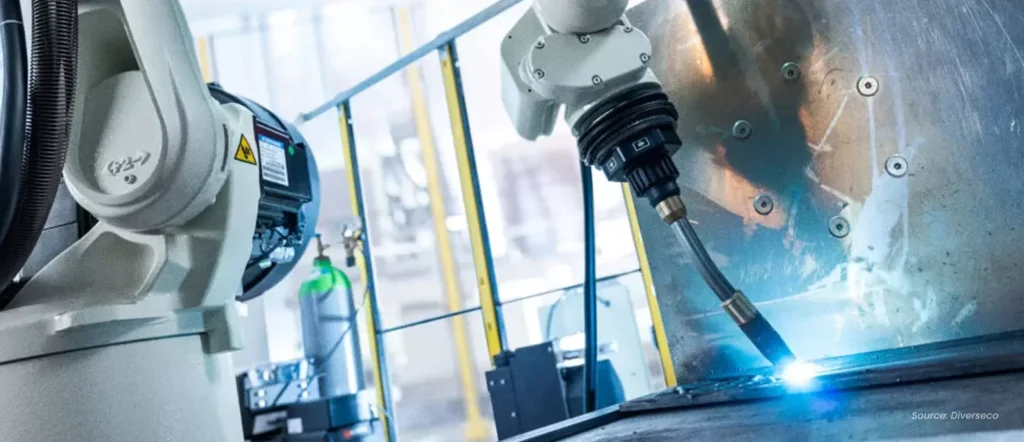 Industrial robot arm performing automated welding inside a factory, showcasing traditional robot automation in contrast to collaborative CoBots